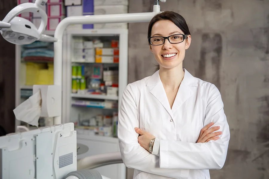 Smiling dentist standing with arms crossed.